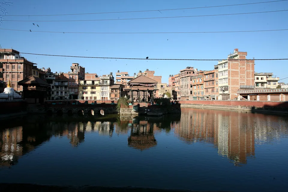 The pavilion and surrounding brick buildings reflected in Pimbahal Pond.